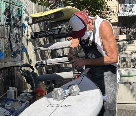 Surfboard being sanded during ding repair